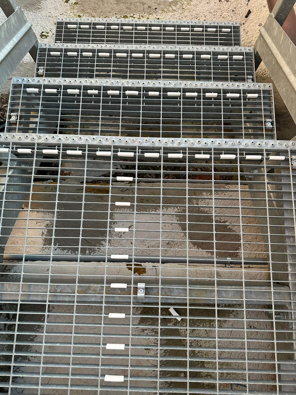 Posizionamento delle clips bianche antipanico sulle scale in grigliato